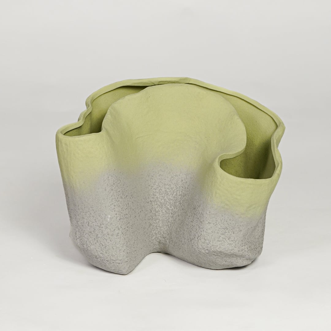 Green ceramic sculpted decorative vase with organic wavy form isolated on clean white background for modern decor styling.