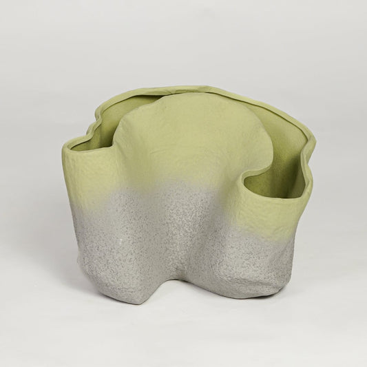 Green ceramic sculpted decorative vase with organic wavy form isolated on clean white background for modern decor styling.