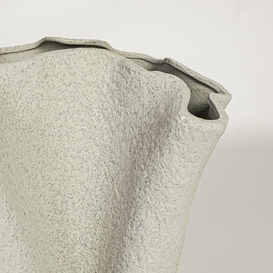 Close view of light beige ceramic vase highlighting textured matte surface and sculpted rim detail for modern decor styling.