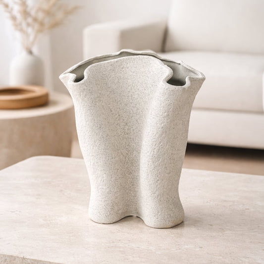 Light beige textured ceramic decorative vase styled with dried stems on console table in modern living room setting.