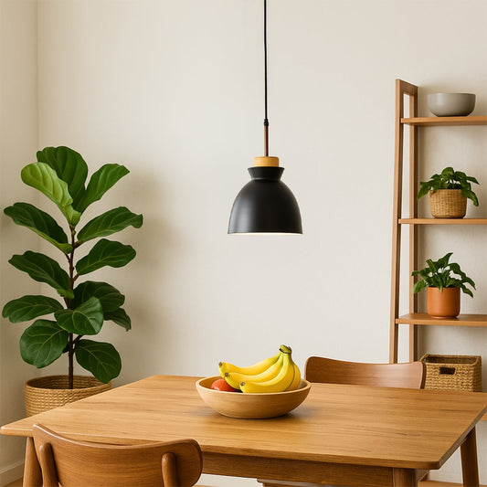 Black metal and wood pendant light hanging above a wooden dining table creating warm ambient lighting in a modern minimalist home interior.