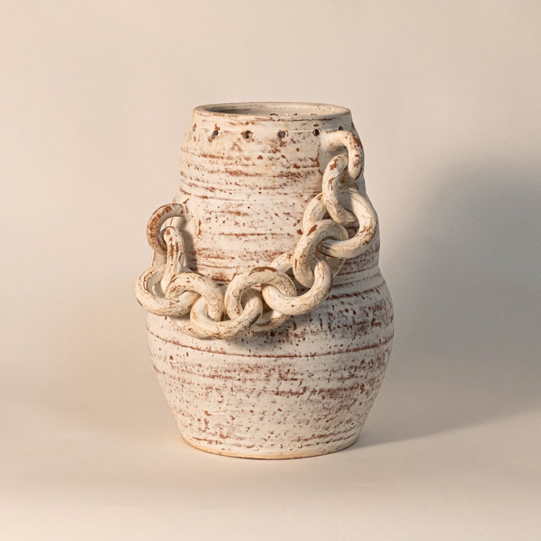 Chain vase displayed on off-white background surface under soft lighting emphasizing its rustic finish and handcrafted details.