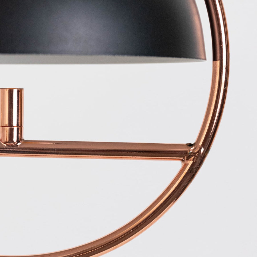 Closeup of designer black and gold pendant ceiling lamp with dome shaped metal shade and golden round frame design.