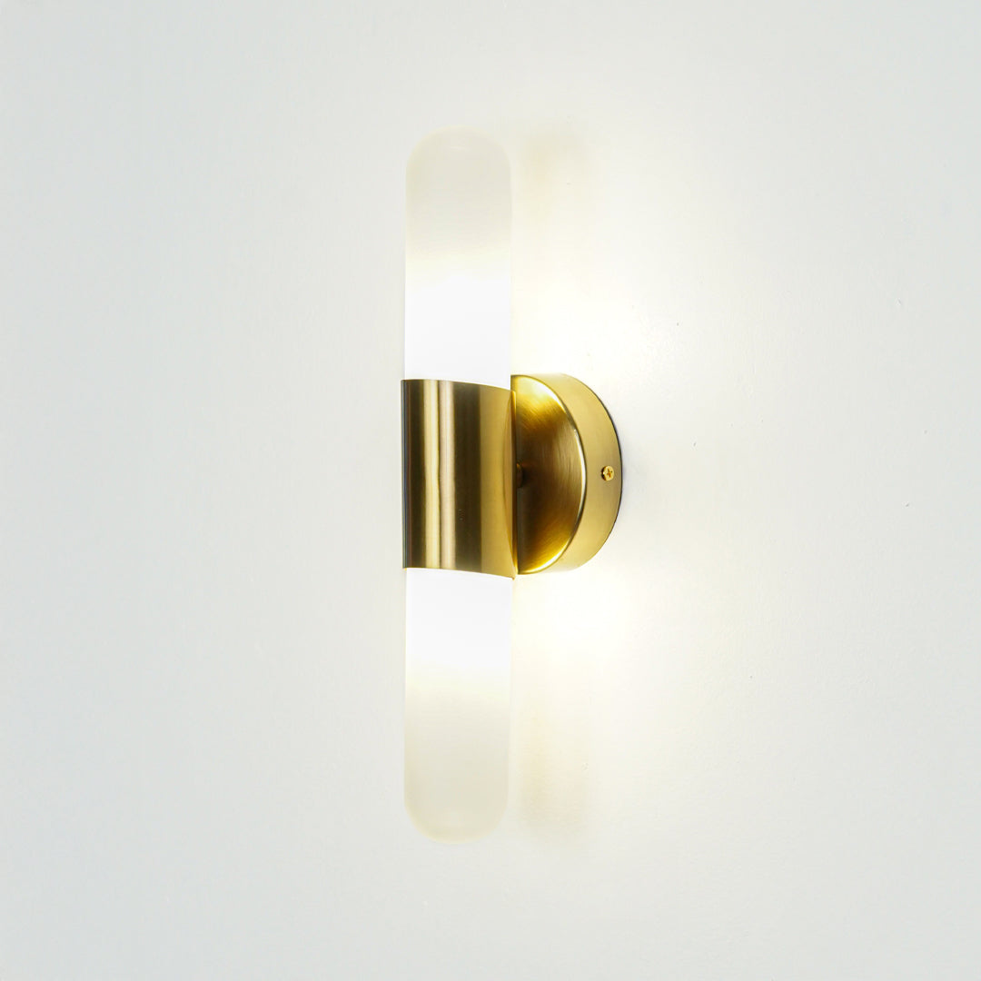 Gold wall light with vertical frosted glass tube mounted on neutral wall background ideal for modern bedroom or hallway lighting.
