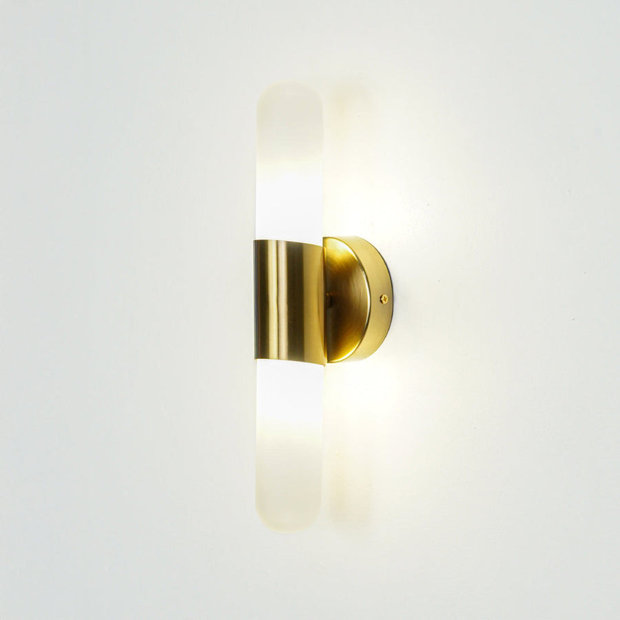 Gold wall light with vertical frosted glass tube mounted on neutral wall background ideal for modern bedroom or hallway lighting.