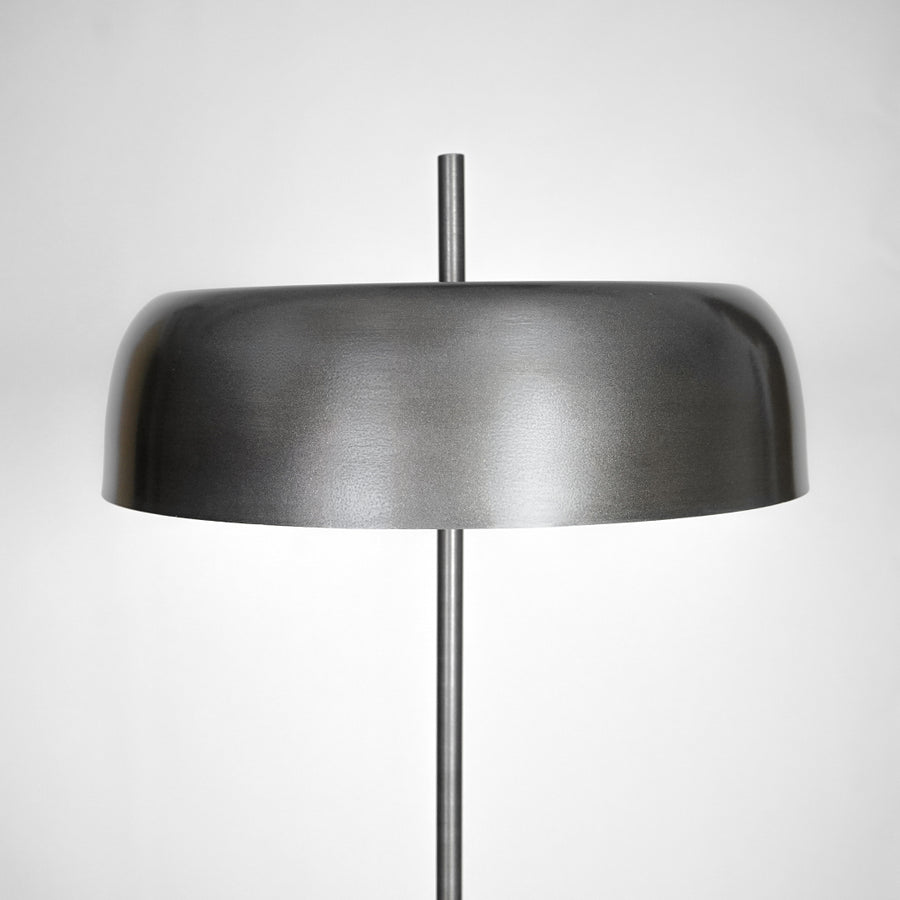 Closeup of black metal table lamp with wide dome shade for bedside table and modern home decor lighting display.