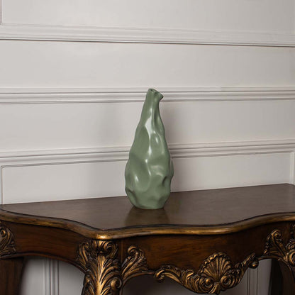 Green sculpted vase placed on a clean white background showcasing its fluid handcrafted look and unique artistic curves that add a stylish modern touch to home decor.