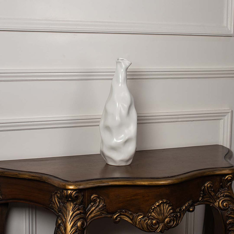 A sculpted white ceramic vase showcased on a plain white background  emphasizing its tall organic form and smooth handcrafted texture.