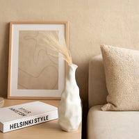 A sculpted white ceramic vase displayed elegantly in a modern setting  highlighting its artistic uneven form for stylish home decor accents.