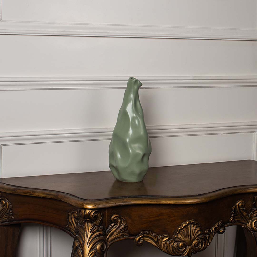 Green sculpted vase placed on a clean white background showcasing its fluid handcrafted look and unique artistic curves that add a stylish modern touch to home decor.