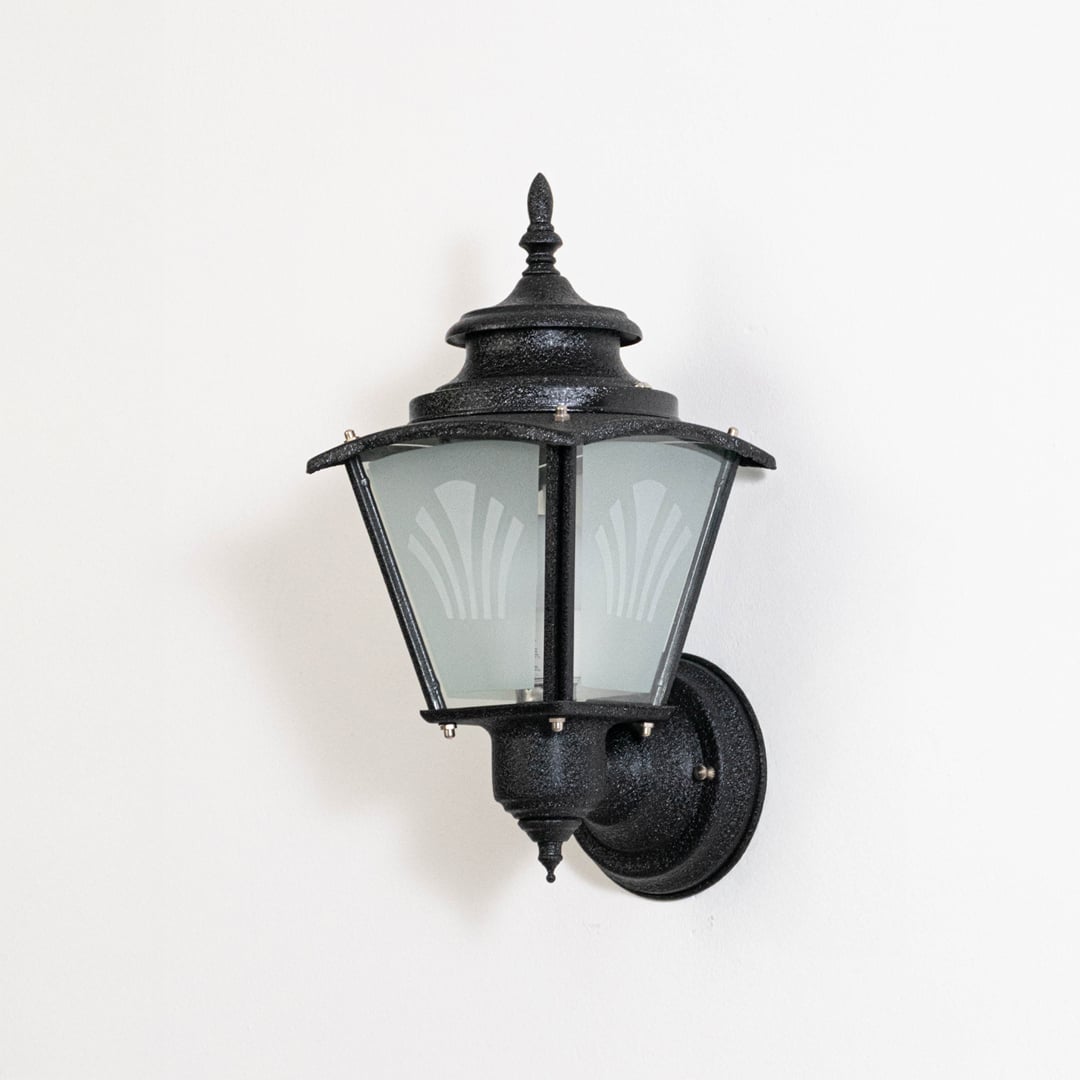 Black metal wall mounted outdoor lantern switched off on white background emphasizing classic shape and weather ready finish.