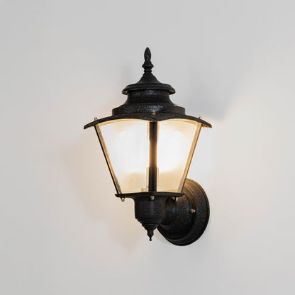 Black metal outdoor wall light on white background with clear glass shade for modern patio lighting decor.