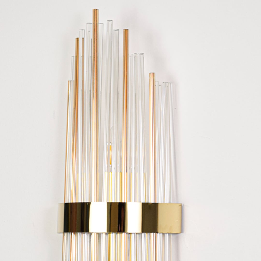 Closeup of modern gold metal wall light with crystal glass and steel brackets highlighting precision build and luxury indoor wall lighting style.