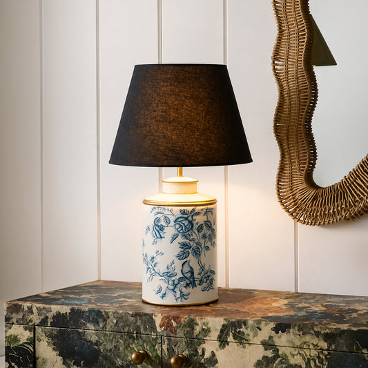 Blue and white floral ceramic table lamp with black fabric shade enhancing luxury living room decor with warm illumination.