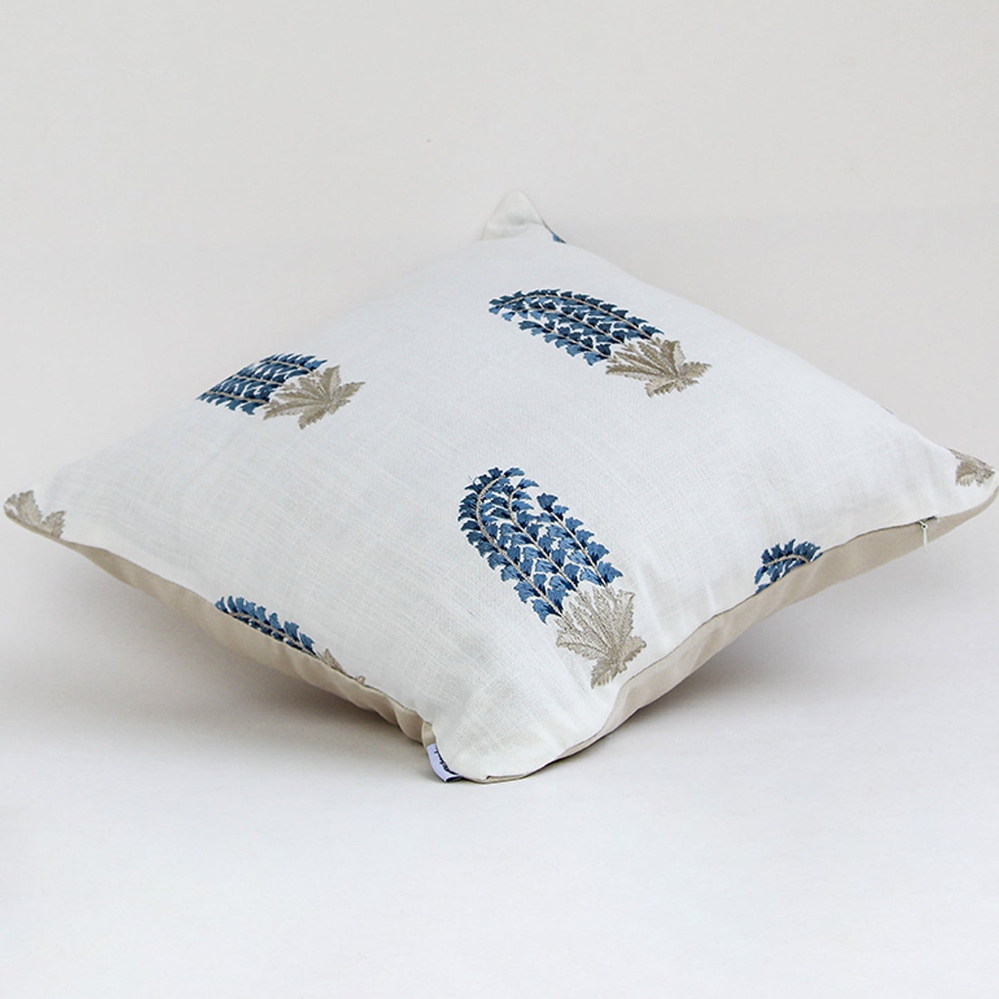 White cushion cover featuring repeating blue floral motifs smooth fabric finish and modern decorative cushion design on white background.