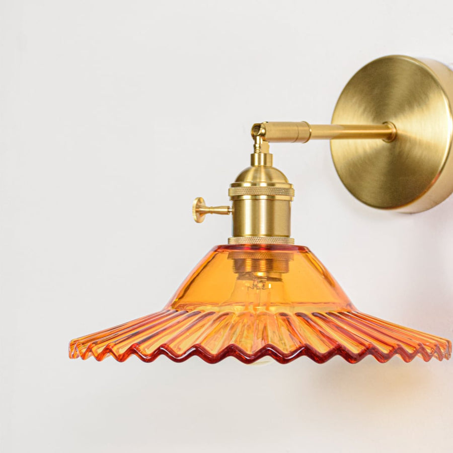 Amber glass wall lamp closeup showing fluted shade and gold metal holder detail designed for classic indoor accent lighting.