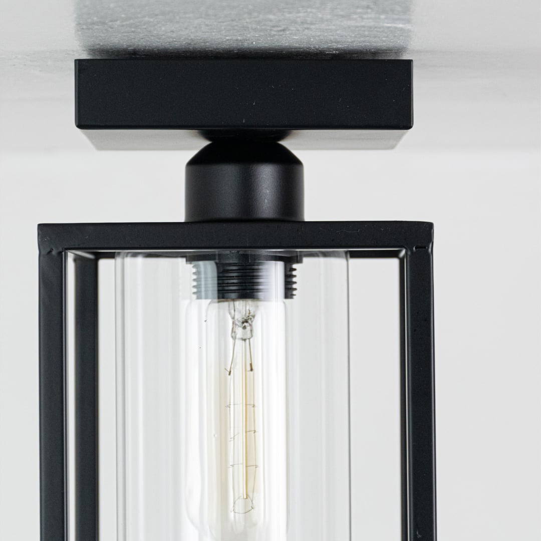 Closeup of black metal outdoor ceiling light highlighting the clear glass cylinder and sturdy metal frame designed for durable exterior lighting.