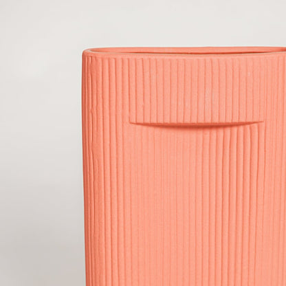Closeup of matte coral ceramic vase with fine lined detailing ideal for elegant home decor shelf or side table styling.