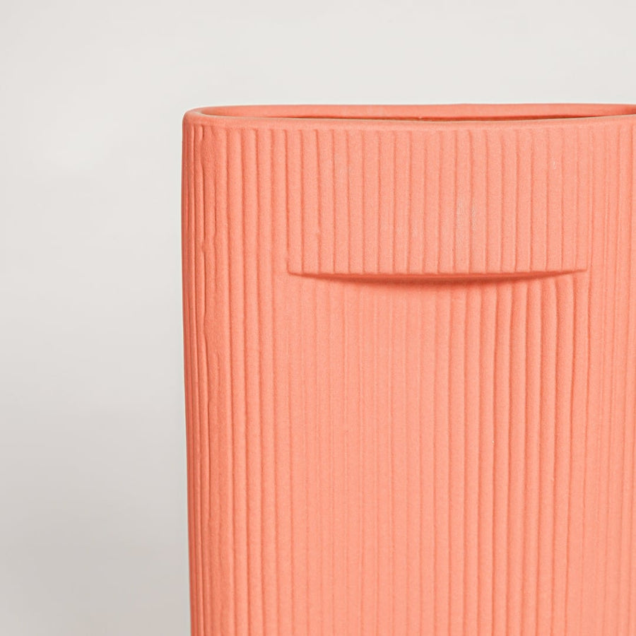 Closeup of matte coral ceramic vase with fine lined detailing ideal for elegant home decor shelf or side table styling.