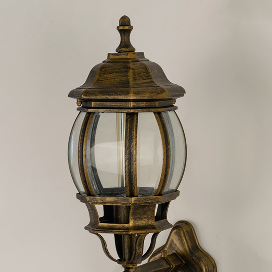 Closeup view of antique gold metal finish and intricate scroll details of the traditional outdoor wall lantern fixture.