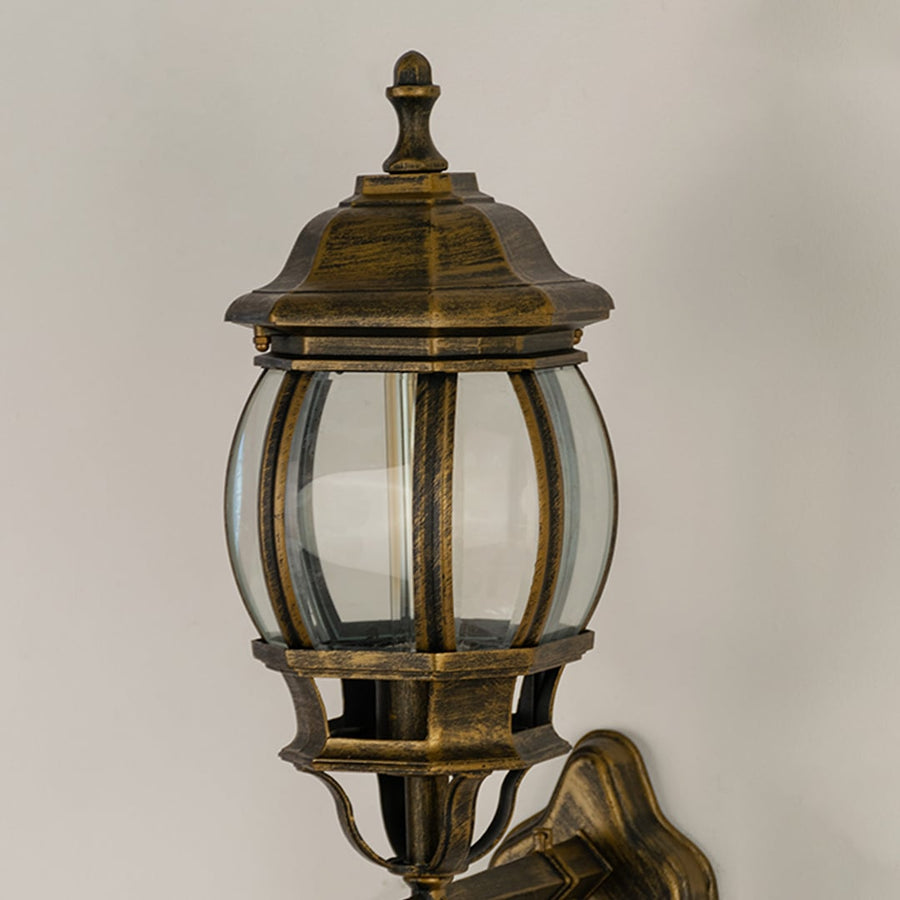 Closeup view of antique gold metal finish and intricate scroll details of the traditional outdoor wall lantern fixture.