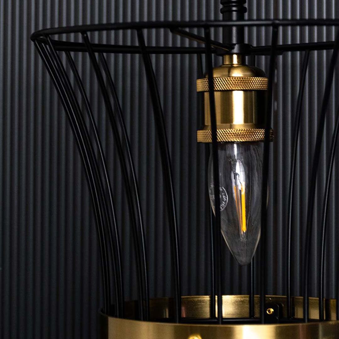 Detailed view of black cage pendant light showing curved wire structure brass detailing and warm glowing bulb creating a refined modern aesthetic.