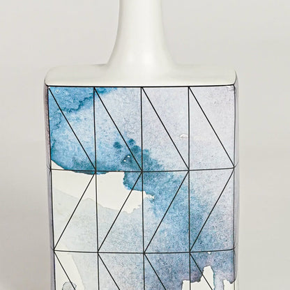 Closeup image of white ceramic artistic vase with blue geometric detailing for modern tabletop decor styling.