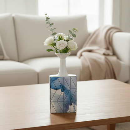 White and blue ceramic flower vase with fresh blooms placed on wooden table for elegant home decor styling.