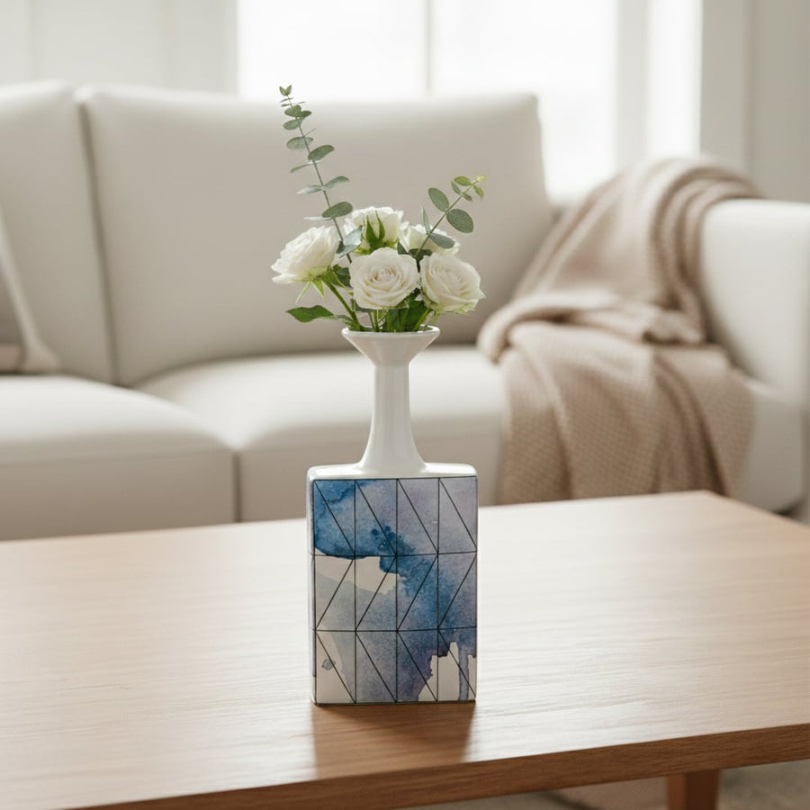 White and blue ceramic flower vase with fresh blooms placed on wooden table for elegant home decor styling.