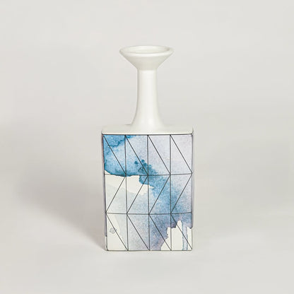 Blue glass bottle vase for modern shelf placement and elegant indoor home decor styling accent piece.