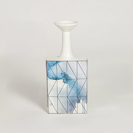 Blue glass bottle vase for modern shelf placement and elegant indoor home decor styling accent piece.