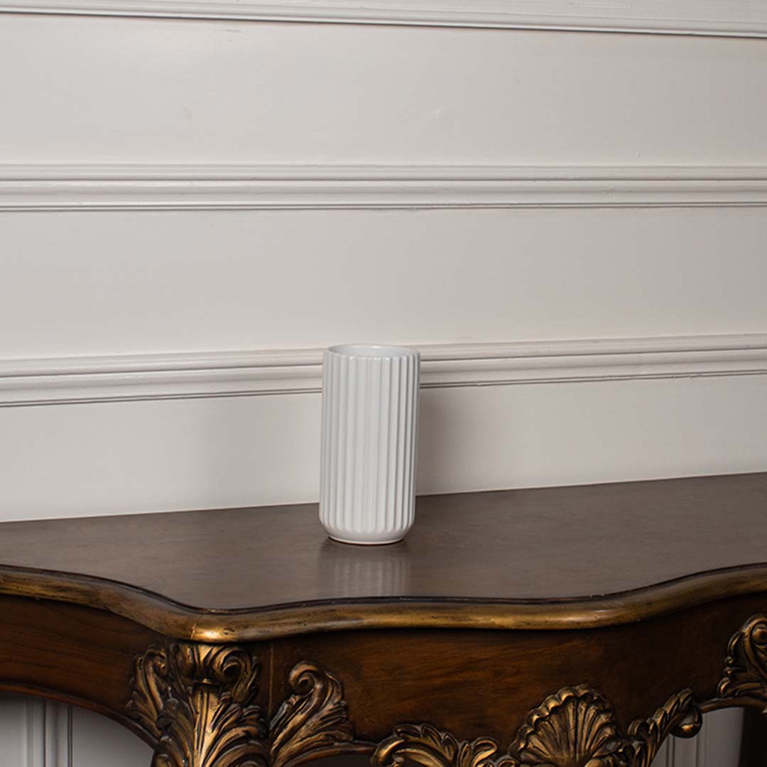 White ribbed ceramic vase displayed on a plain white background showing its clean cylindrical shape and simple modern texture.