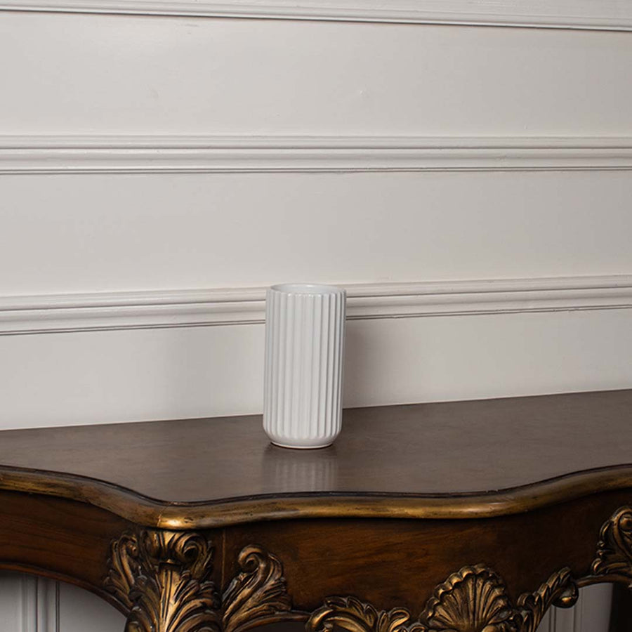 White ribbed ceramic vase displayed on a plain white background showing its clean cylindrical shape and simple modern texture.