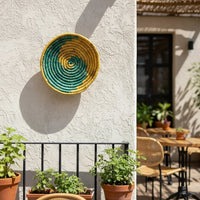 Colorful woven wall basket mounted on exterior wall above plants creating artistic focal point for balcony and patio Decor.