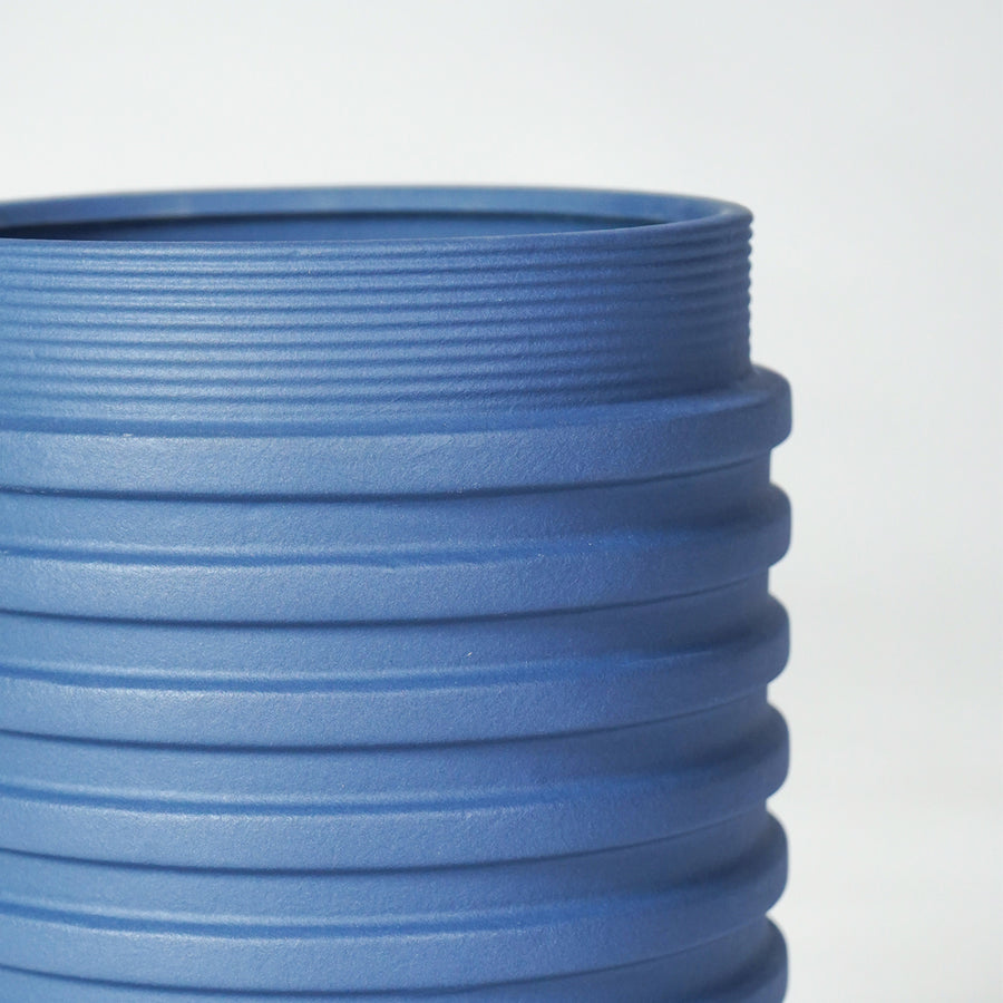 Closeup image of blue ceramic ribbed planter vase for modern shelf decor styling with artistic matte finish.