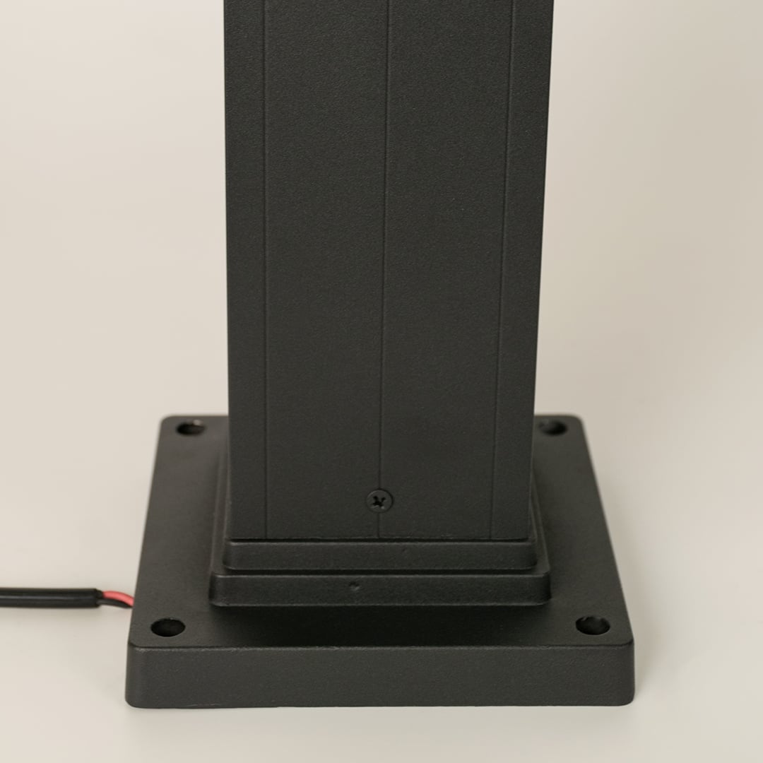 Detailed closeup of black bollard light highlighting its ribbed glass cylinder and solid metal frame for contemporary outdoor illumination.