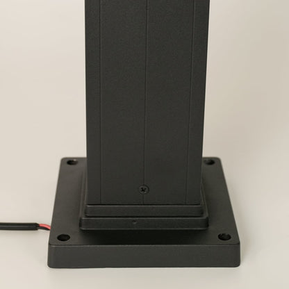 Detailed closeup of black bollard light highlighting its ribbed glass cylinder and solid metal frame for contemporary outdoor illumination.