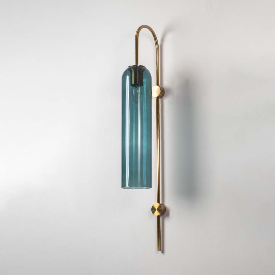 Teal glass and gold metal wall light with bulb off on a clean white background highlighting its slim cylinder shade and minimal contemporary form.