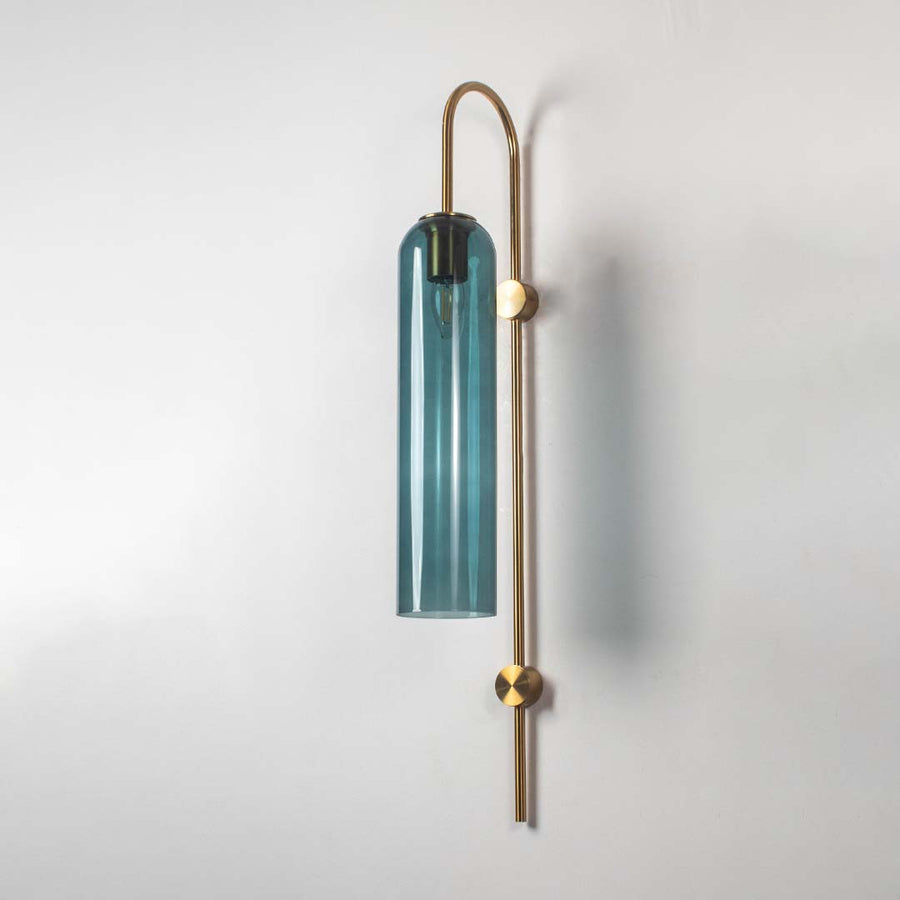Teal glass and gold metal wall light with bulb off on a clean white background highlighting its slim cylinder shade and minimal contemporary form.