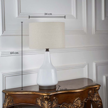 White ceramic table lamp with fabric shade shown on a wooden table with marked dimensions including 64 cm height and 34 cm shade width against a white background.