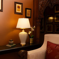 Beige lamp on wooden table with light on and warm rustic wall background for vintage cozy décor.
