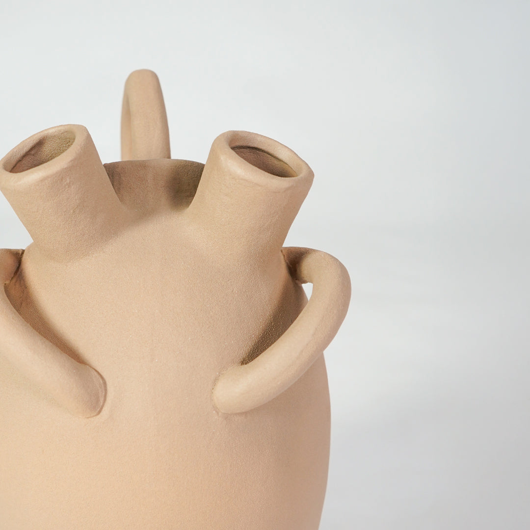 Closeup image of beige ceramic multi spout vase for modern tabletop decor styling with earthy matte finish.