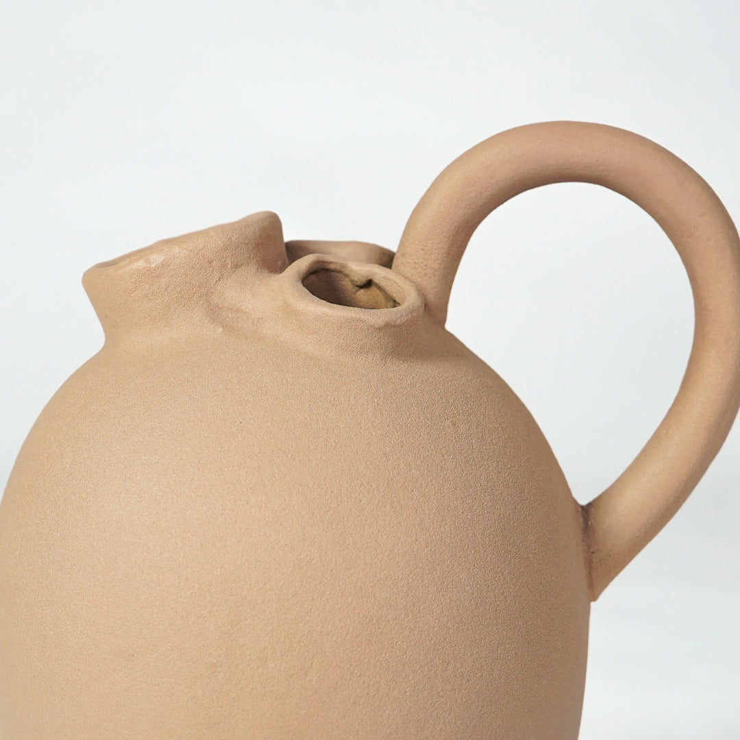 Closeup image of beige ceramic jug vase for rustic tabletop decor styling with natural matte textured finish.