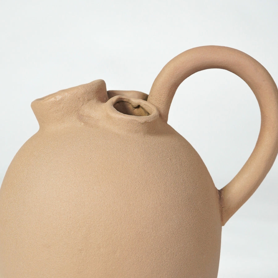 Closeup image of beige ceramic jug vase for rustic tabletop decor styling with natural matte textured finish.