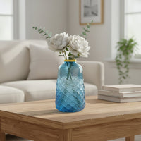 Blue glass decorative vase styled with fresh flowers on a coffee table for elegant modern home decor arrangements.