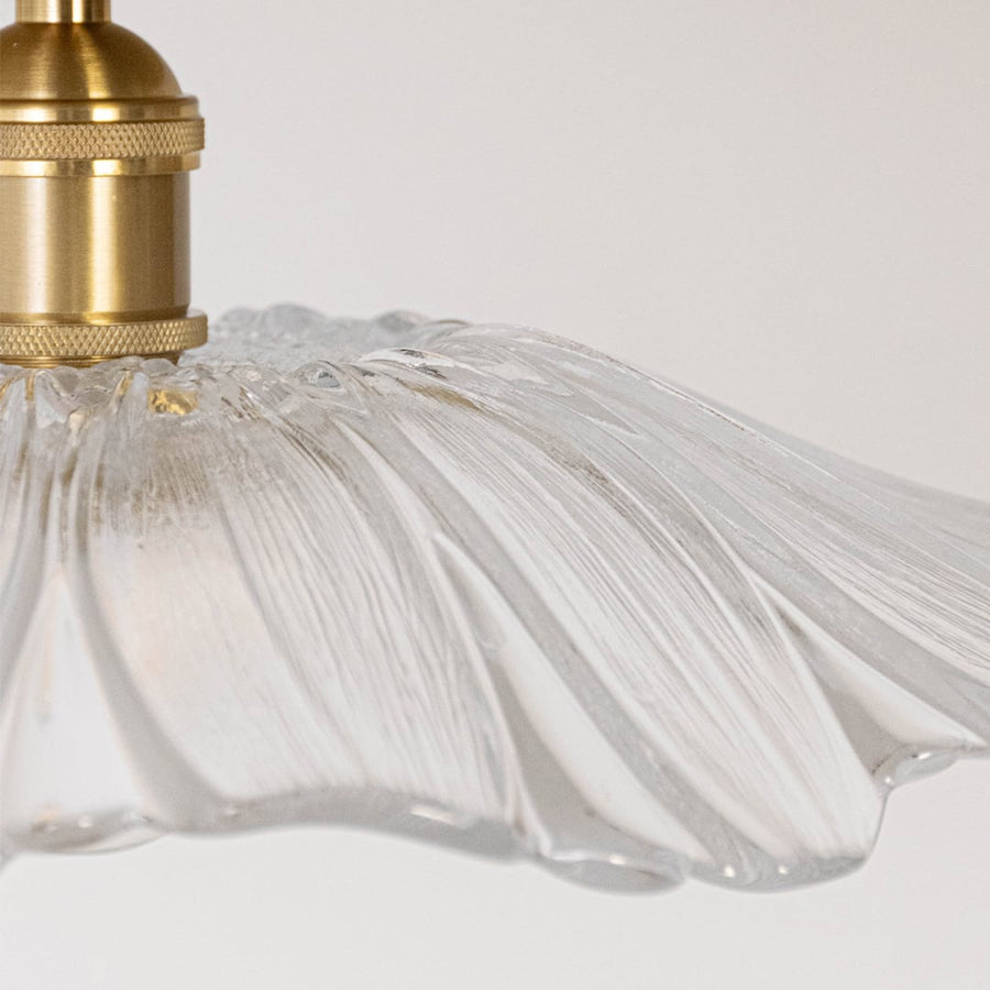 Closeup of ceiling light with brushed gold holder and decorative flower glass shade for modern home lighting decor.