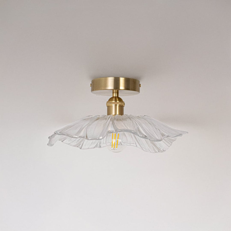 Ceiling light with brushed gold base and petal shaped glass shade shown switched off on plain white background.