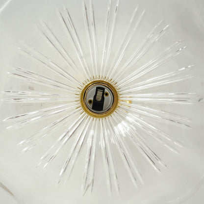 A close-up of a starburst-style clear glass ceiling light fixture with radiating glass rays and a central brass socket.