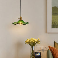 Green glass pendant light suspended above side table adding elegant ambient lighting to modern living room decor.