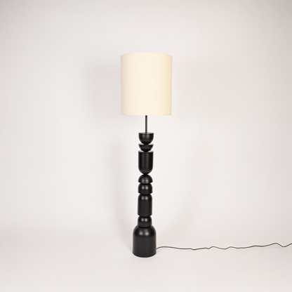 Floor lamp off on white background showcasing stacked sculptural base with tall fabric shade for clean minimalist product display.